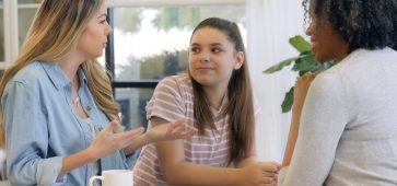 Mom discusses issues with daughter’s counselor Mom gestures as she discusses her teenage daughter's progress in counseling. The counselor has a pleased expression on her face.